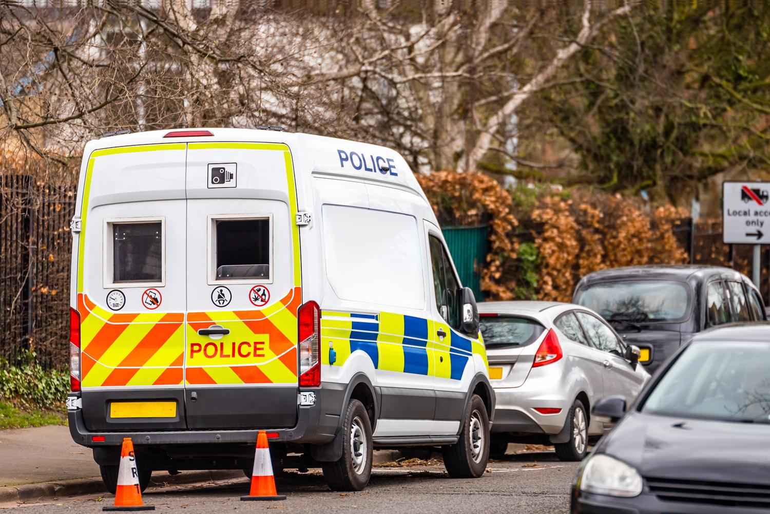 Police van parked on a street with traffic cones placed nearby.