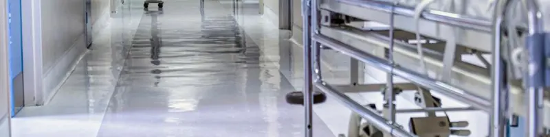 Hospital corridor with an empty stretcher and a chair in the distance.