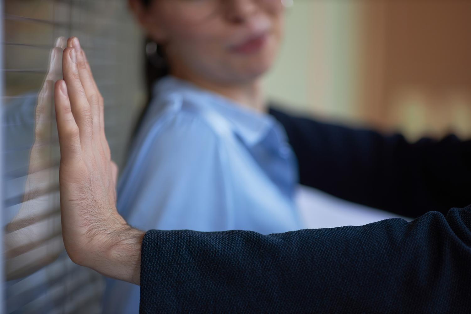 Close-up of a man blocking a woman against a wall with his arm.