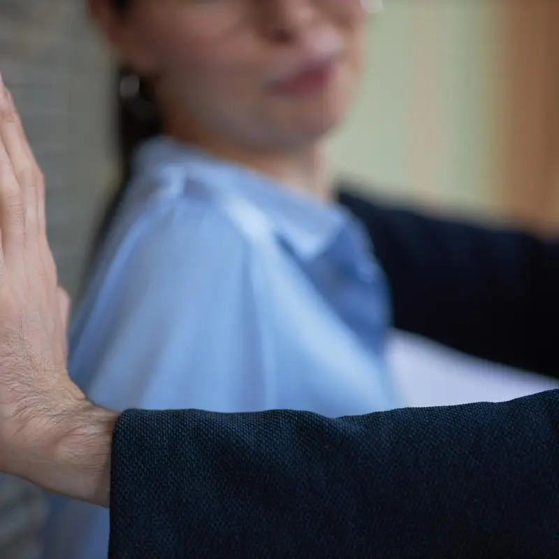Close-up of a man blocking a woman against a wall with his arm.