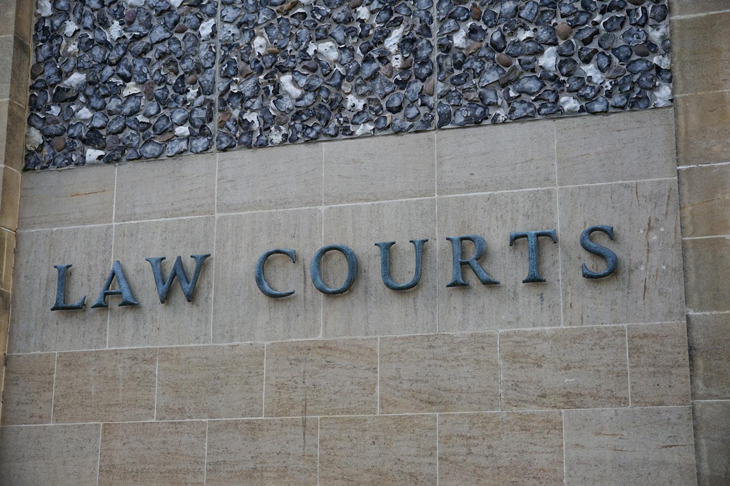 Stone wall with 'LAW COURTS' engraved, marking a courthouse entrance.