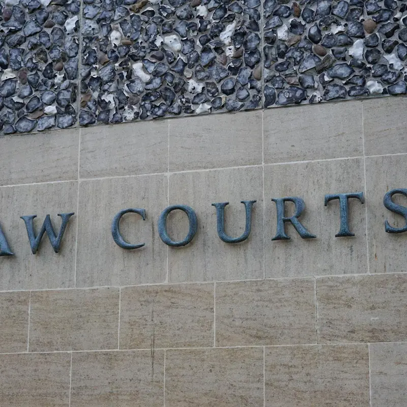 Stone wall with 'LAW COURTS' engraved, marking a courthouse entrance.