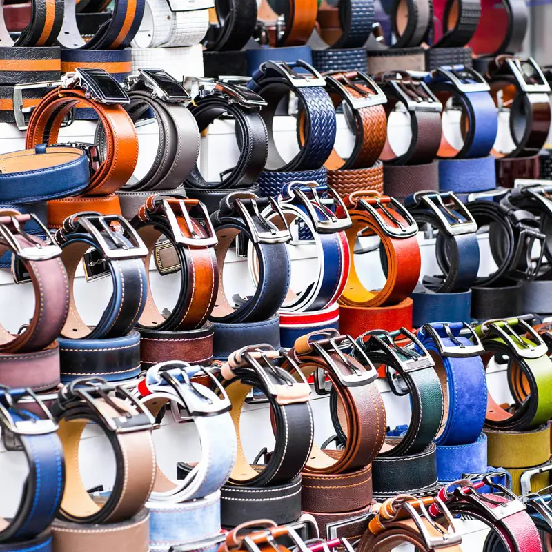 Display of various leather belts with metal buckles at a market stall.