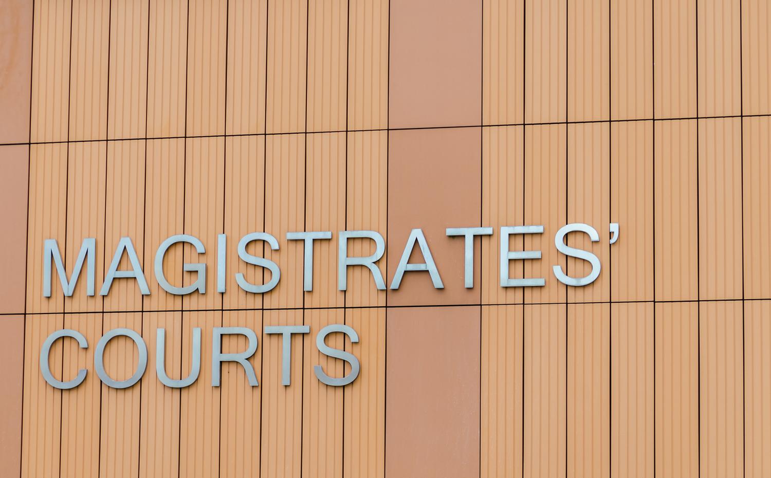 Sign reading 'MAGISTRATES' COURTS' on a modern building facade.