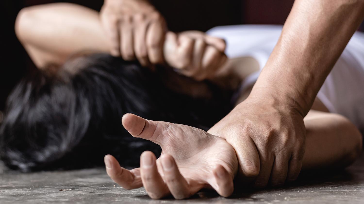 Depiction of physical restraint, showing a close-up of hands held down.