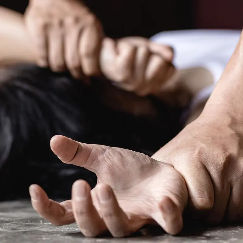 Depiction of physical restraint, showing a close-up of hands held down.