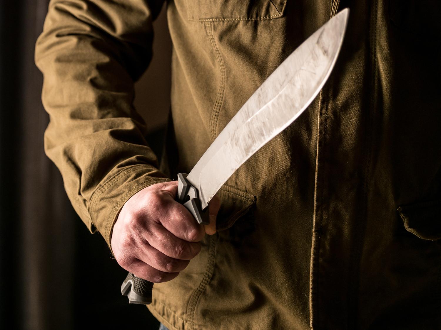 Close-up of a person holding a large knife with a firm grip.