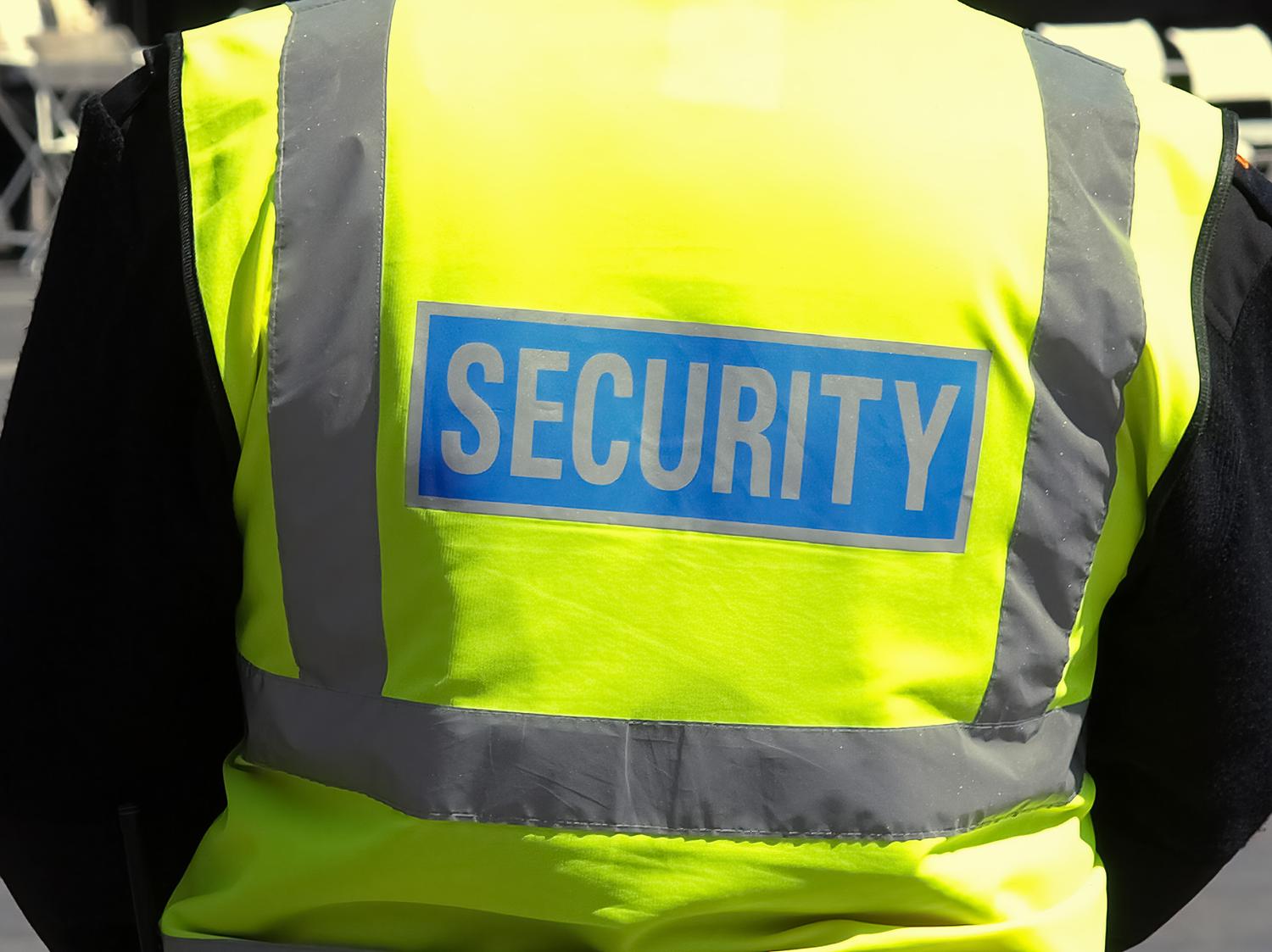 Security guard wearing a high-visibility vest with 'SECURITY' printed on the back.
